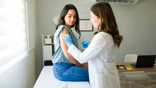 Professional medical worker wearing gloves is vaccinating a young woman in a doctor's office