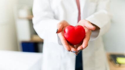 Caring woman doctor holds a vibrant red heart, representing compassion and empathy in healthcare