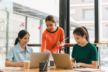 Collaborative women working together in modern office space, sharing ideas and engaging with laptops. Their expressions reflect enthusiasm and teamwork