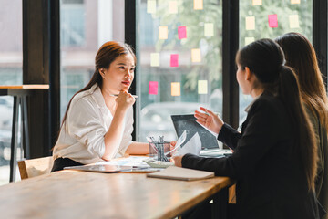 Professional women engaged in business meeting, discussing ideas and strategies at modern workspace. atmosphere is collaborative and focused, with colorful sticky notes in background