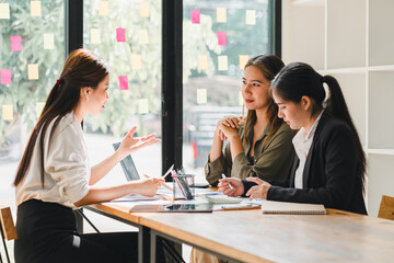 Collaborative meeting with three women discussing ideas at modern workspace. They are engaged in conversation, showcasing teamwork and creativity in bright environment