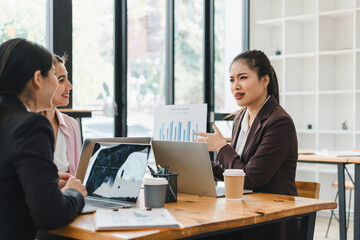 Professional women engaged in business meeting, discussing strategies and analyzing data on laptops. atmosphere is collaborative and focused, highlighting teamwork and communication