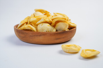A bowl of banana chips sits on a white background