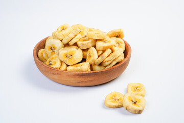 A bowl of banana chips sits on a white table