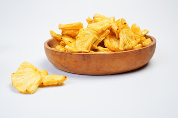 A bowl of pineapple chips sits on a white table