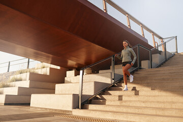A morning runner is seen energetically navigating urban stairs which lie beneath a bridge