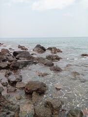 Portrait of a beach scene on a sunny day with rocks on the shore