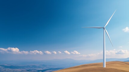 Obraz premium A solitary wind turbine stands on a hillside against a bright blue sky, symbolizing renewable energy and a sustainable future.