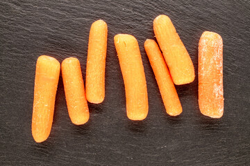 Small peeled carrot on slate stone, macro, top view.
