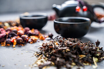 Various herbal dry teas, a teapot and cups on a gray table. Selected focus