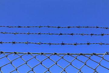 Barb wire fence. Blue sky as background.