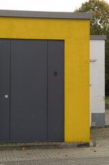 Large gray metallic garage door with yellow wall