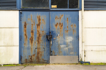Old rusty blue metal door with damaged paint showing corrosion