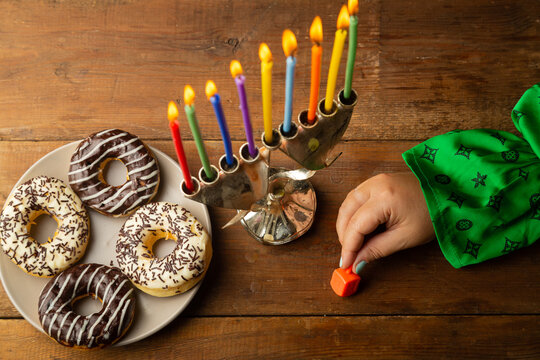 A woman's hand spins a dreidel at the Hanukkah table