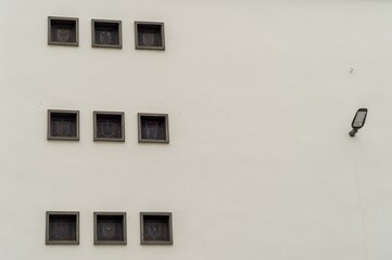White wall showing nine square windows with a lamp on the right side