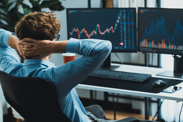 Young investor stock trader leaning body back looking at investing dynamic screen of current market...