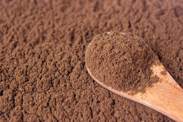 Roasted coffee powder on wooden spoon with coffee powder background, food background. closeup.