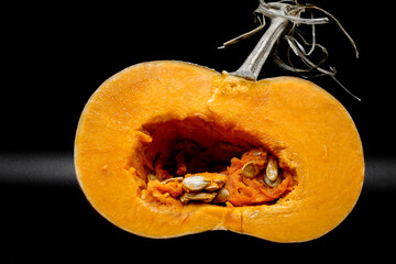 Fresh pumpkin cut on the black background. Seeds and fruit flesh. Natural healthy food. Copy space.