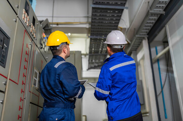 Electrical engineers and technicians work together to solve electrical system failures in industrial control rooms.supervisor maintains the circuit cabinet.