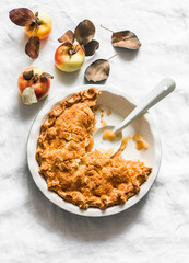 Traditional Irish apple pie in a baking dish, apples on a light background, top view