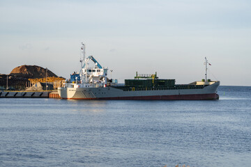 Crane with wood logs gripple loading timber on cargo ship for export. Timber exports. Ship in port.