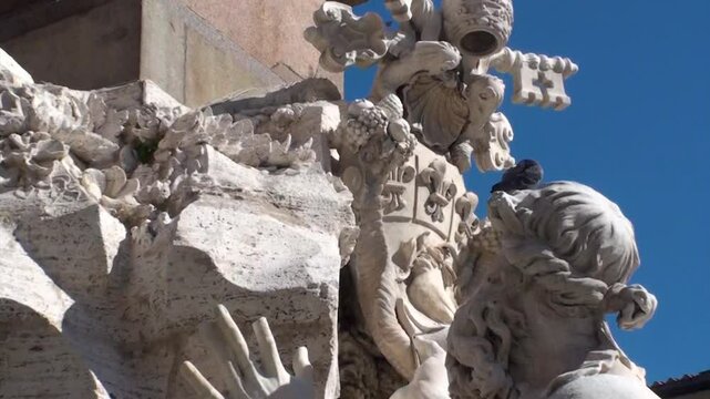 Fontana dei Quattro Fiumi, Piazza Navona: zoom in su stemma papale e piccione sulla testa di una statua, in una giornata di sole splendente