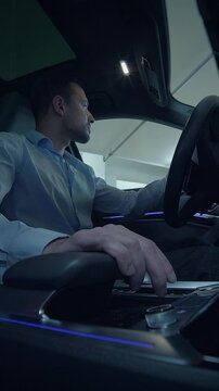 A man is driving a luxurious and stylish car in a contemporary modern urban setting