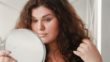 Morning skincare. Natural beauty. Health wellness. Confident overweight woman with clean face skin looking in mirror on light free space.