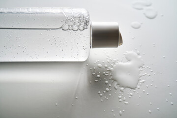 Bottle of facial toner or cleanser on white background with drops of product.