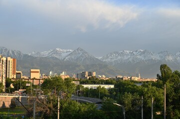 Obraz premium Almaty city skyline. Buildings and mountains illuminated by the setting sun. 