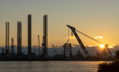 Obraz premium The image captures the industrial might and complexity of the oil and gas industry. The contrast between the man-made structures and the natural beauty of the sunrise creates a thought-provoking scene