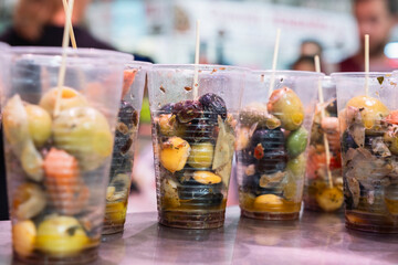Snacks with olives in plastic cups at the food market in Valencia
