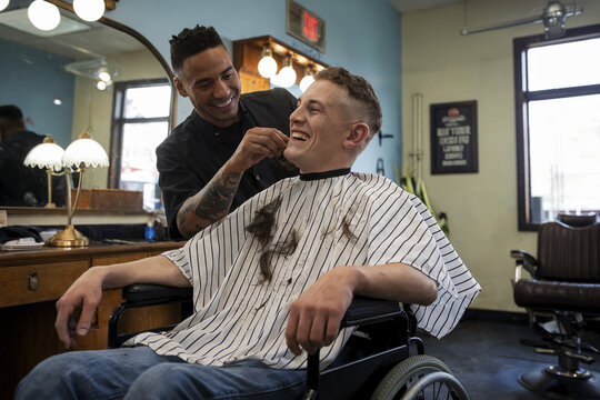 Disabled guy in a wheelchair gets his hair cut at a barbershop.