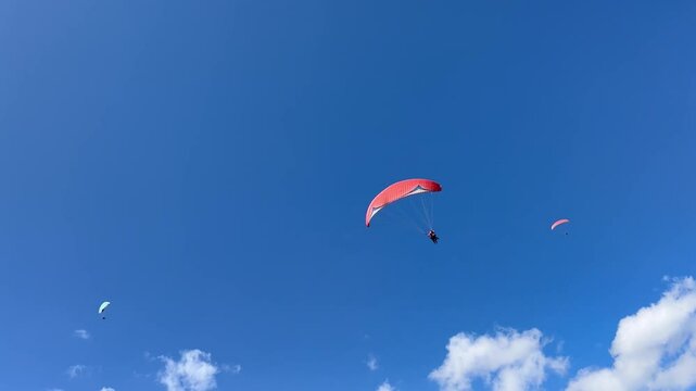 Soaring on a paraglider over the mountains against a clear blue sky. Extreme sports