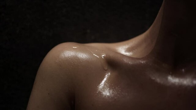 Close-up shot of an attractive woman's collarbone area, with water droplets glistening on her skin. This image conveys a sense of freshness and well-being, perfect for beauty and skincare themes.