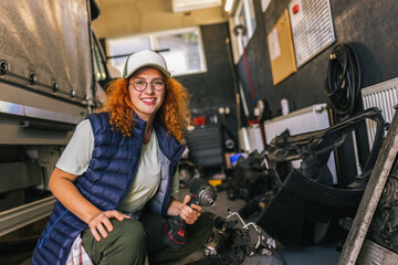 Young ginger woman mechanics repairing the wheel of a truck, combi, long vehicle.
