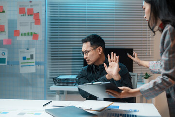 Asian businessman is rejecting an offer from his businesswoman partner while working late at night in the office