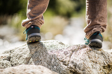 Rear view of hiking shoes on boulders in outdoor landscape