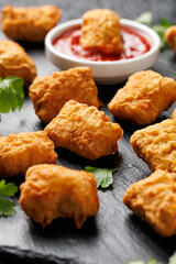 Homemade crispy fried chicken nuggets served on a stone board