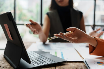 Businesswomen having a discussion about financial data, analyzing charts and statistics displayed on a laptop during a collaborative meeting