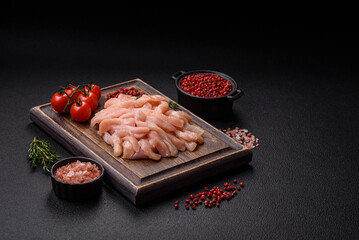 Raw chicken fillet cut into strips with spices and herbs