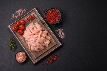 Raw chicken fillet cut into strips with spices and herbs