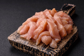Raw chicken fillet cut into strips with spices and herbs