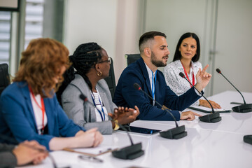 Man CEO talking on the microphone on meeting with his colleagues about business plan, future collaboration.