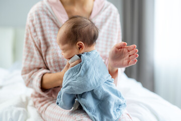 Mother comforting burping baby and sit on the bed