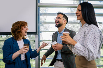 Group of multicultural colleagues standing in the conference room and having coffee break.