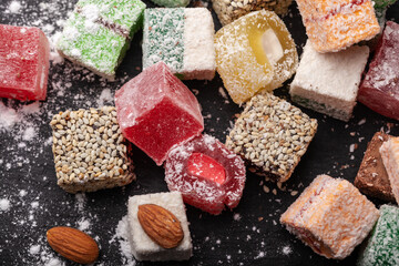 Assortment of Turkish sweets with nuts on a black background. A scattering of Turkish delight