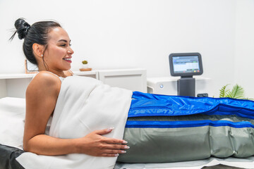 Woman smiling relaxing during pressotherapy treatment in beauty clinic