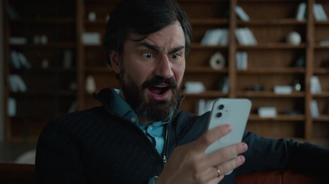 Shocked amazed excited 50s mature middle aged Caucasian business man male businessman hold smartphone use mobile cell phone receive amazing news win game victory online bet offer prize winning indoors