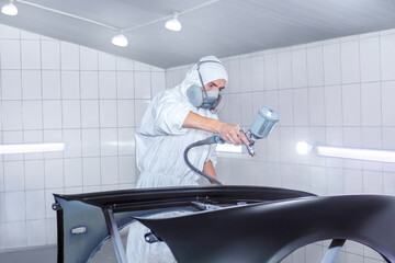 Professional Auto Painter Spraying Car Body in Specialized Workshop Booth